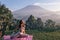 Woman with dark hair in sportive suit making yoga on sunrise with volcano Agung view