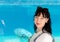 Woman, dark-haired, European, middle-aged, stands in front of a blue aquarium