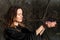 Woman with dark long hair in black robes is holding polished Shungite Sphere in her hands in front of the lake