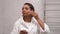 A woman with dark skin washes her face with foam and water in the bathroom.