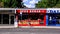 Woman And Daughter Walking Past A Takeaway Kebab Shop