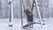 Woman and daughter on wooden swings in winter