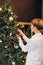 woman decorates Christmas tree garlands bright items