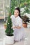 A woman decorates a live Christmas tree in a flower pot