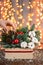 Woman decorates Small arrangement of fresh spruce in a rustic wooden box. Christmas mood. Bokeh of Garland, lamps lights
