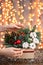 Woman decorates Small arrangement of fresh spruce in a rustic wooden box. Christmas mood. Bokeh of Garland, lamps lights