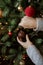 Woman decorating christmas tree with  bauble closeup. Preparation for christmas time. Modern glitter ornament in hands on