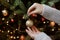 Woman decorating christmas tree with shiny golden bauble closeup. Preparation for christmas time. Modern glitter ornament in hands