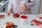 Woman decorating sweet bagel with jam with strawberries and heart-shaped candies. Preparing surprise breakfast for lover