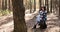 Woman deep breathing resting, sitting in chair with tourist backpack in pine forest in sun shin