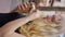 A woman delicately eats ice cream in a waffle cone using her hand and spoon