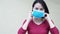 Woman demonstrate how to put on protective mask for corona virus prevention, standing on white background copy-space. waring mask