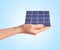 Woman demonstrating solar panel on blue background, closeup. Alternative energy source