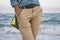 Woman in denim shirt and beige trousers walking along the beach