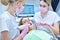 Woman dentist and assistant scaning patient`s teeth with  3d scanner