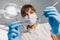 Woman dentist in blue face mask and gloves examine teeth with probe and mirror. View from patient seat to doctor