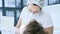 Woman Dentist doctor in glasses mask and white cap examines the oral cavity of the patient. Dentist`s work