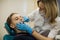 Woman dentist doing teeth checkup of boy in a dental chair at medical clinic.