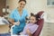 Woman dentist and girl patient showing thumbs up sign and smiling during teeth examination in dentist office