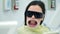 Woman in dentistry with retractor in her mouth and sunglasses waiting a doctor.