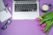 Woman desktop with Laptop, morning coffee and tulips on violet b