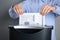 Woman destroying newspaper with shredder on grey background, closeup