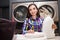 Woman with detergent bottle in laundromat. Quality laundry detergent concept