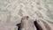 Woman digging with feet in the sand. Person playing burying his feet in dry sand