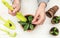 A woman is digging the soil in a plant pot on a white wooden background. Growing flowers and plants in pots. Home hobby