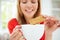 Woman Dipping Biscuit Into Hot Drink At Home