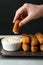 Woman dipping cheese stick into sauce at table,