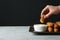 Woman dipping cheese stick into sauce at table. Space for text