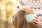 Woman dipping cookie in a coffee mug in autumn