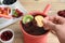 Woman dipping cookie and kiwi slice into pot with chocolate fondue at table