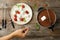 Woman dipping marshmallow into pot with chocolate fondue on wooden background