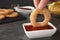 Woman dipping onion ring into hot chili sauce in bowl