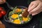 Woman dipping piece of bread into egg yolk, closeup. Eating tasty Shakshuka