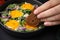 Woman dipping piece of bread into egg yolk, closeup. Eating tasty Shakshuka