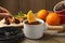 Woman dipping slice of orange into fondue pot with milk chocolate at wooden table