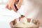 Woman dipping strawberry into bowl with white chocolate fondue, closeup