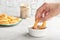 Woman dipping tasty onion ring into bowl