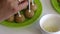 A woman dips her stick into melted white chocolate and fixes it in a popcake billet. Blanks are located on the plate.