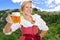 Woman in dirndl with beer in front of the Alps