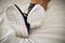 Woman in dirty sports shoes lying on a clean white bed cover in a hotel bedroom