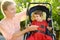 Woman with disabled girl in a wheelchair walking in the summer park. Child cerebral palsy. Disability. Inclusion. Means of