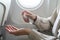 Woman disinfects hands apply alcohol sanitizer, on board of an airplane. New Normal, safety and travel transport during COVID-19