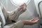 Woman disinfects hands apply alcohol sanitizer, on board of an airplane. New Normal, safety and travel transport during COVID-19