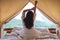 A woman do stretching after waking up in the morning  , looking at a beautiful nature view outside the tent