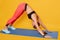 Woman do yoga Downward Facing Dog pose insolated over yellow studio background, beautiful slim and sporty female strengthening