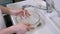 Woman doctor beautician in robe pours water into a large bowl to wash the face